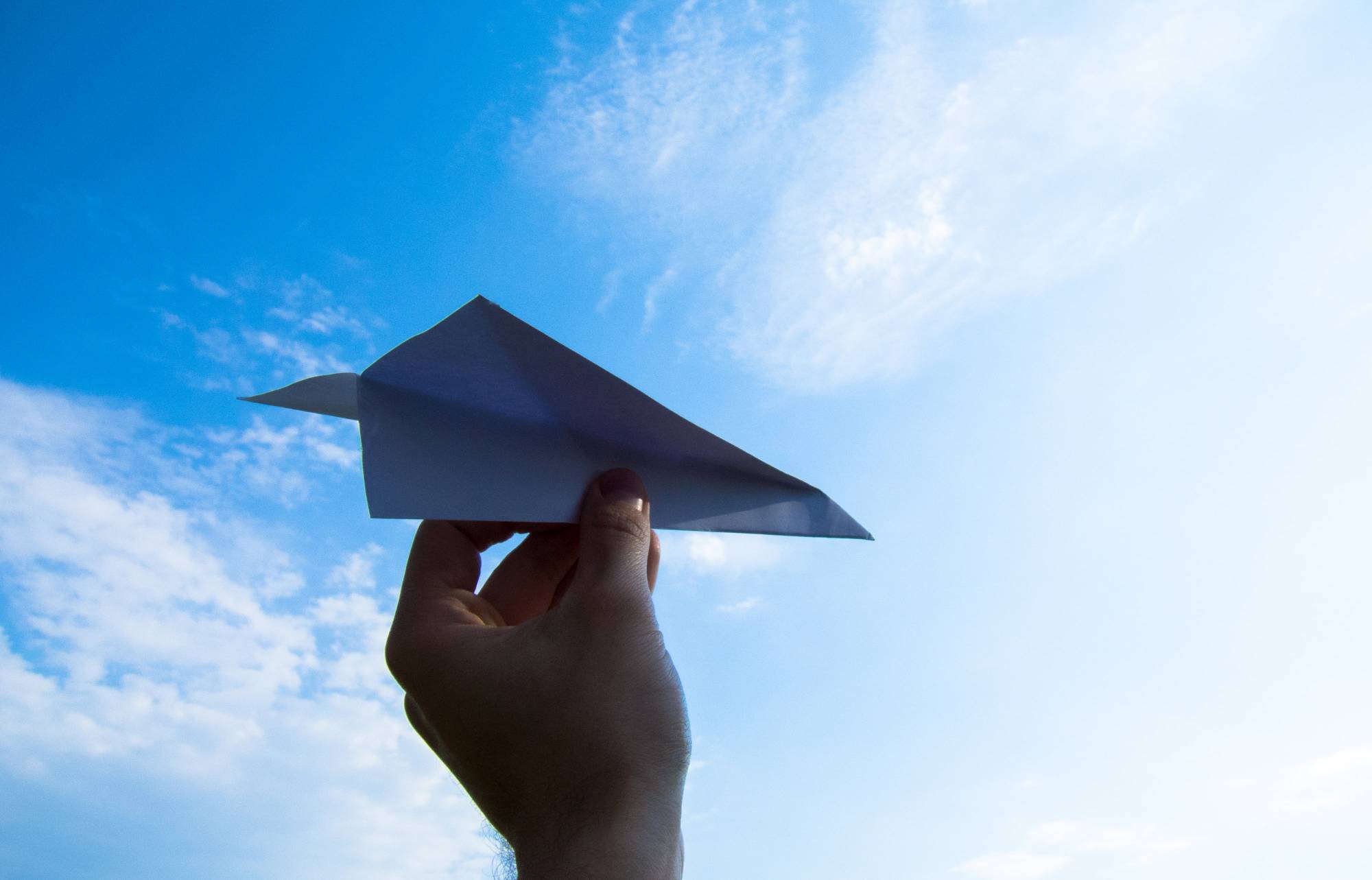 空に向けて紙飛行機を飛ばすところ